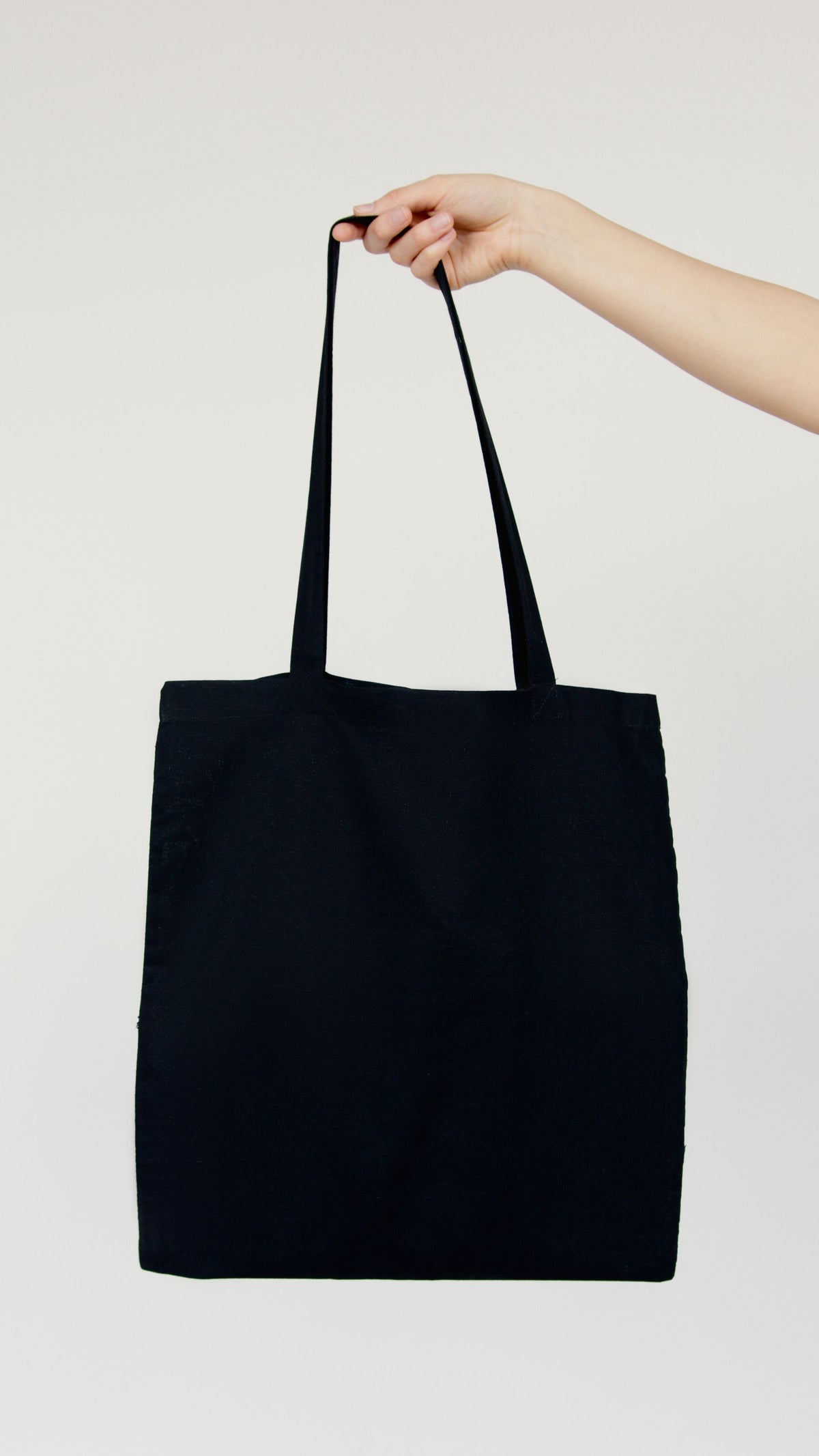 A plain canvas tote held up before branding